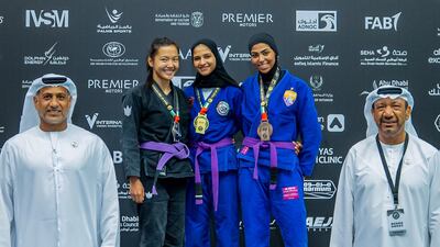 Asma Al Hosani, centre, on the podium flanked by Aigerim Kuatkyzy, left, and Bashayar Al Matrooshi. Photo: UAEJJF