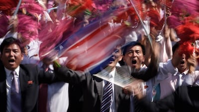 Participants wave flowers as they march past a balcony from where North Korea's leader Kim Jong Un was watching, during a mass rally on Kim Il Sung square in Pyongyang. AFP