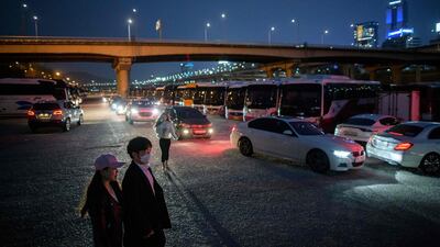 A couple walk between cars queuing for a screening at a drive-through cinema in Seoul. AFP