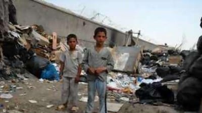 Habib Gul and Rahman Gul stand among the rubbish they helped their father, Sher Gul, to collect.