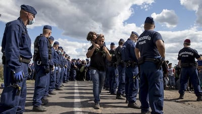 A migrant carries a child through rows of Hungarian police. Marko Djurica / Reuters