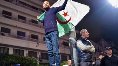 TOPSHOT - An Algerian stands with a national flag during a demonstration in the centre of the capital Algiers on March 11, 2019, after President Abdelaziz Bouteflika announced his withdrawal from a bid to win another term in office and postponed an April 18 election, following weeks of protests against his candidacy. Bouteflika, in a message carried by national news agency APS, said the presidential poll would follow a national conference on political and constitutional reform to be drawn up by the end of 2019. / AFP / RYAD KRAMDI