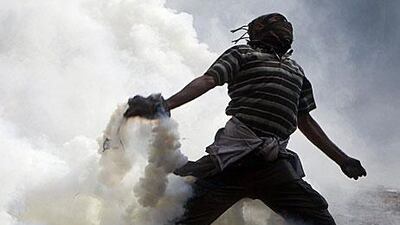 A protester throws a tear gas canister, earlier thrown by riot police, during clashes near Tahrir Square yesterday.