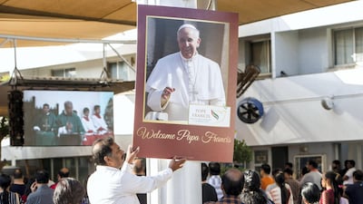 A volunteer arranges a papal poster.