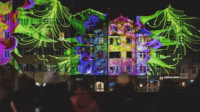 People watch the facades of houses at Mariahilf illuminated to celebrate the New Year 2023 in Innsbruck, Austria, on December 31, 2022. AFP