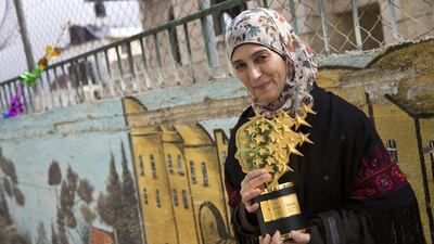 Hanan Al Hroub holds her Global Teacher trophy in the Samiha Khalil schoolyard in Al Bireh, just outside Ramallah after her award win in 2016. Heidi Levine for The National