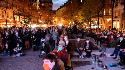 People gather on the Place de la Sorbonne in Paris on October 21, 2020, to watch a live broadcast on a giant screen of a national homage at the Sorbonne University to French teacher Samuel Paty, who was beheaded for showing cartoons of the Prophet Mohamed in his civics class. AFP
