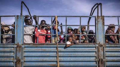 Refugees who have fled from the war in Sudan stand on a truck arriving at a Transit Centre