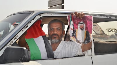 A driver in Aden holds the UAE flag and a portrait of the President, Sheikh Khalifa, to show his gratitude. Mohammed Al Qalisi for The National