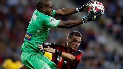 Lille's Nigerian goalkeeper Vincent Enyeama, left, catches the ball in front of Nice forward Eric Bautheac during a French Ligue 1 football match on September 24, 2014 at the "Allianz Riviera" stadium in Nice, southeastern France. AFP PHOTO / VALERY HACHE