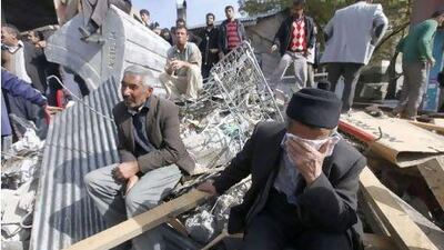 Survivors sit amid rubble in the town of Ercis, where at least 80 apartment buildings collapsed in Sunday's earthquake.