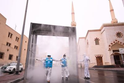 Health volunteers pass through a sterilisation chamber installed to disinfect residents entering and leaving the Naif area in Dubai during the Covid-19 outbreak in April, 2020. Karim Sahib / AFP