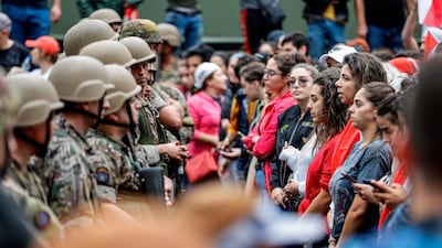 Female protesters stand in a line before Lebanese army soldiers during a demonstration on the seventh day of unrest against tax increases and official corruption, in Zouk Mosbeh, north of Beirut. AFP