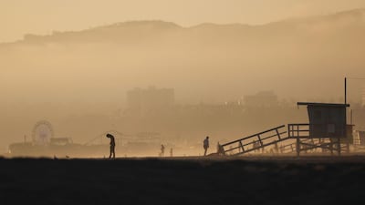 People gather as the Sun sets on the mostly empty Venice Beach, California. AFP