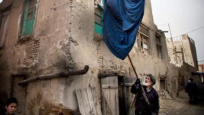 Haji Hussain, 75, who colours clothing for 40 years, takes a freshly colored burqa out for drying outside his small shop.