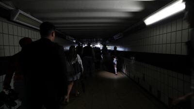 People walk in near darkness at Clapham Junction station in London during the country-wide power cut on August 9 that report says was caused by a lightning strike. AP