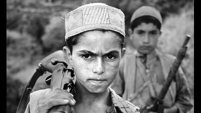 A young boy stands with his firearm, 1979. Copyright ©Steve McCurry / Magnum Photos