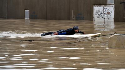 A man uses a paddleboard on a flooded after a heavy downpour on the main road near Rafic Hariri International Airport at the southern entrance of Beirut. EPA