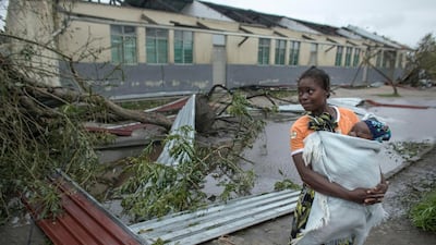 A local resident carries her chilld past debris at the secondary school used as an emergency shelter for local residents in the village of Inhamizua, Mozambique. CARE/ EPA