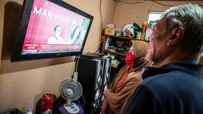 Indonesians watch a television showing live news of Indonesian President Joko Widodo receiving his Covid-19 vaccine shot in Jakarta, Indonesia. Reuters