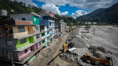 Heavy machinery is used to clear mud and sand near the banks of the Teesta river in Rongpo, Sikkim state, after houses and bridges were washed away. AP