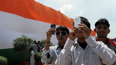 Young Indian men take photos with their mobile phones at the India Gate monument in New Delhi during Independence day celebrations on August 15, 2012. Roberto Schmidt / AFP Photo