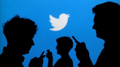 People holding mobile phones are silhouetted against a backdrop projected with the Twitter logo in this illustration picture. Reuters