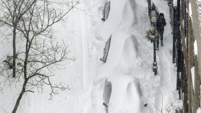 A snow shoveller tries to clear a spot in the middle of a city street beside snow-covered vehicles during the winter snowstorm in Boston. AP Photo/Steven Senne