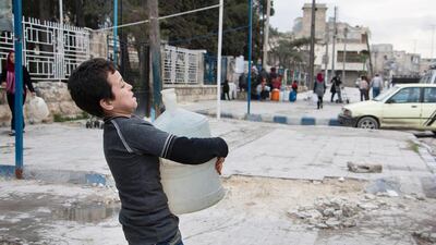 A Syrian boy carries a container filled with water in the rebel-held side of the northern city of Aleppo, where despite a temporary ceasefire, citizens on both sides of the fault line dividing Aleppo between regime and rebel forces are suffering from their longest water shortage yet in the nearly five-year war. Karam Al Masri/AFP