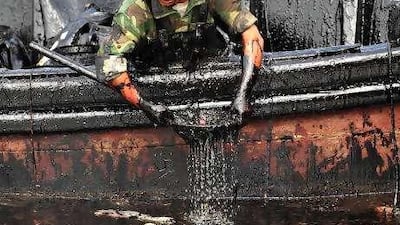 A member of a clean-up team scoops oil from the sea near near Dalian Port, off Liaoning province, in north-east China.