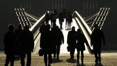 Pedestrians are silhouetted in the winter sun, as they walk onto the Millennium Bridge across the River Thames.