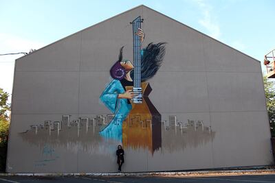 Shamsia Hassani in 2018 next to a finished mural in Eugene, Oregon, USA. Courtesy Shamsia Hassani