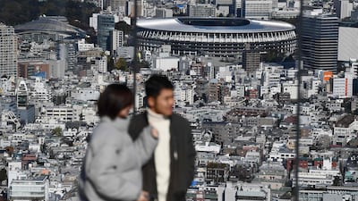 People at a viewing area look out at the completed Tokyo 2020 Olympic Games stadium. AFP