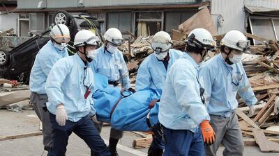 Rescue team members carry a dead body in Ofunato, Japan.