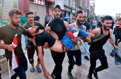 An injured protester is carried after tear gas was fired by security forces during a protest in Tahrir Square, in central Baghdad, Iraq, on Tuesday. AP