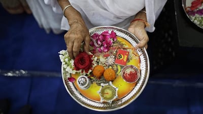 A woman holds a plate with rakhis, sweets and oil lamps. AP