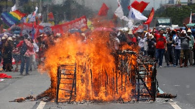 Anti-government protesters chant slogans in front of the remains of a burning effigy of a tank during a rally near the Philippine Congress. Erik De Castro / Reuters