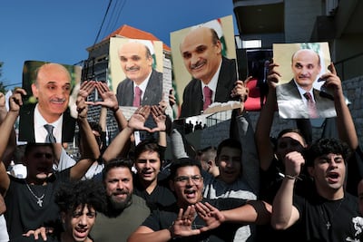 Supporters of Samir Geagea, the leader of the Christian Lebanese Forces party, chant slogans as they hold his photo after he declined to show up for questioning over deadly clashes in Beirut earlier this month, outside his residence in Maarab east Beirut, Lebanon, Wednesday, Oct. 27, 2021. AP
