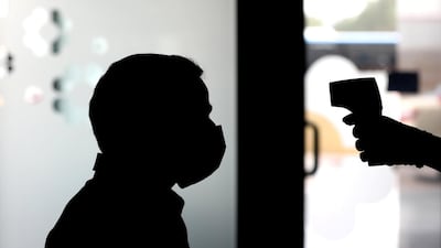 A patient has his temperature checked at the NMC Royal Hospital. Chris Whiteoak / The National