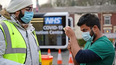 A health worker draws up a dose of a Covid-19 shot at a drive-through vaccination centre outside Ewood Park, Blackburn Rovers FC's ground, in north-west England. AFP