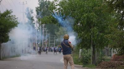 An Indian police man fires tear gas shell at Kashmir protesters near the site of a gunbattle in Pulwama, south of Srinagar, Indian controlled Kashmir, Thursday, May 16, 2019. (AP Photo/ Dar Yasin)