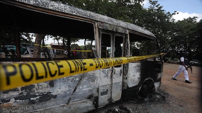 A police officer walks beside a burnt prison vehicle. AFP