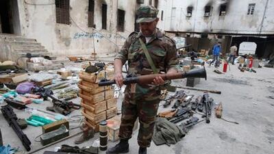 An anti-government protester wearing a military uniform holds up an RPG launcher that was brought back after it was stolen from a military unit as people bring back stolen weapons to a state security building taken over by anti-government protesters in Benghazi.