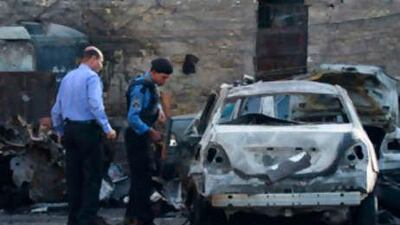 Policemen inspect a burnt vehicle at the site of a bomb attack in Baghdad's Karrada district on Sept 29, 2008.