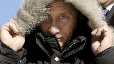 Putin warms himself during his visit to the native village of famous Russian writer Viktor Astafiev in Ovsianka on February 27, 2004. AFP