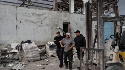 Security guards help an injured man following a Russian bombing of a factory in Kramatorsk. AP