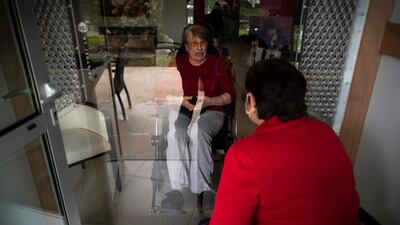 A woman speaks with her mother in a visiting room fitted with window during a visit in an accommodation facility for dependent elderly on April 21, 2020, in Toulouse, France. AFP