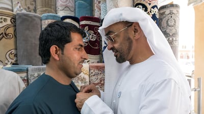 Sheikh Mohammed bin Zayed, Crown Prince of Abu Dhabi and Deputy Supreme Commander of the Armed Forces, puts a 'Year of Zayed' pin on a staff member at Al Safa Carpet shop, in the carpet market of the Mina Zayed Port. Ryan Carter for the Crown Prince Court - Abu Dhabi