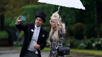 Racegoers take cover from the heavy rain under an umbrella as they pose for a selfie during day four of Royal Ascot at Ascot Racecourse. Andrew Matthews/PA Wire