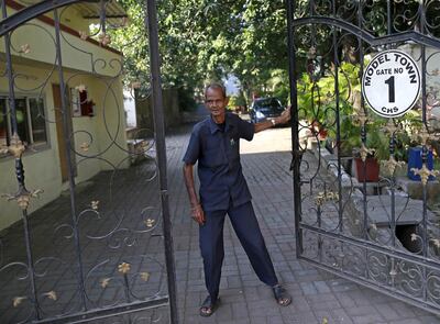 An elederly watchman opens the gate for a resident at a housing society in Mumbai, India. Reuters